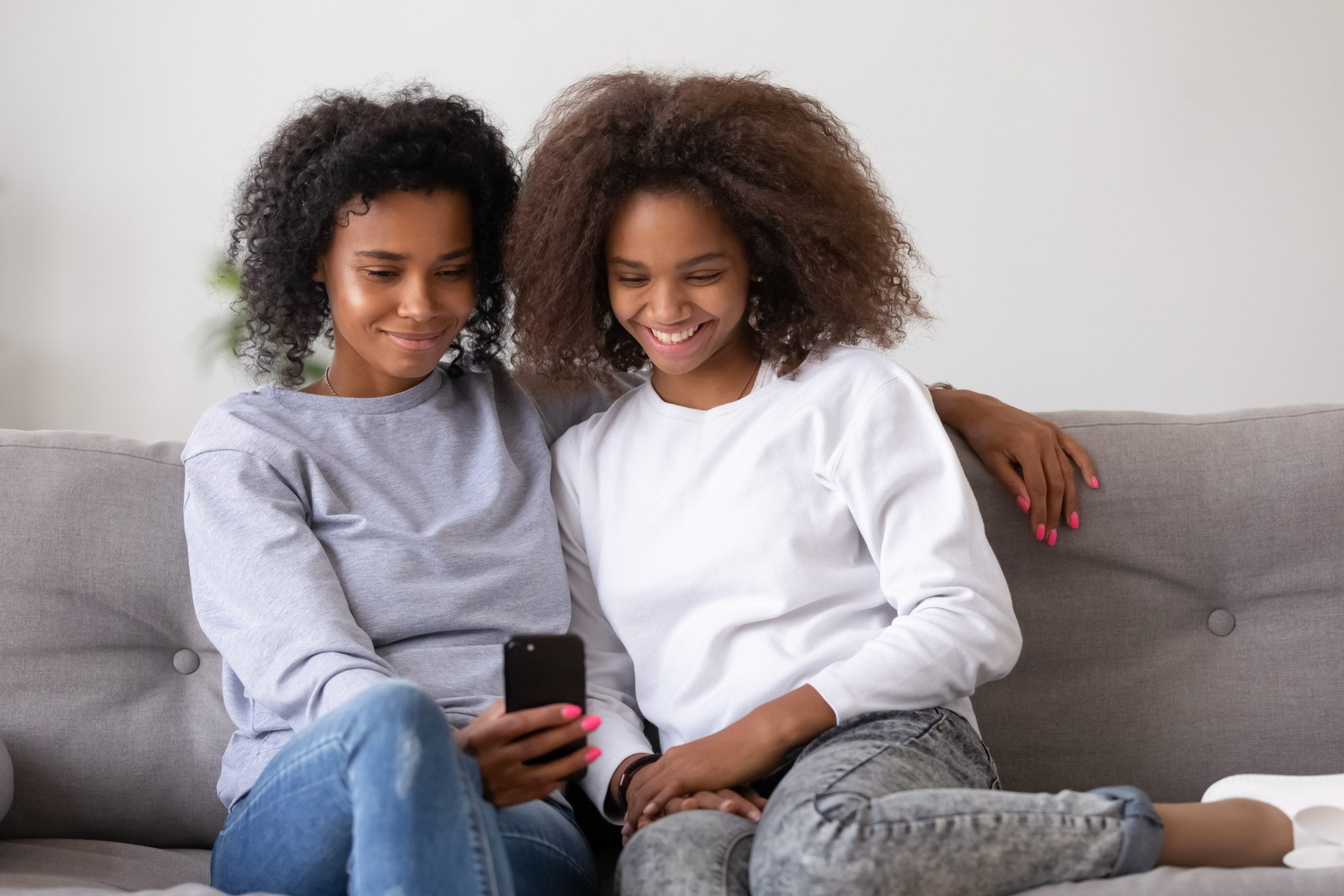 Smiling african american mother and teen daughter using smartphone apps child custody attorneys